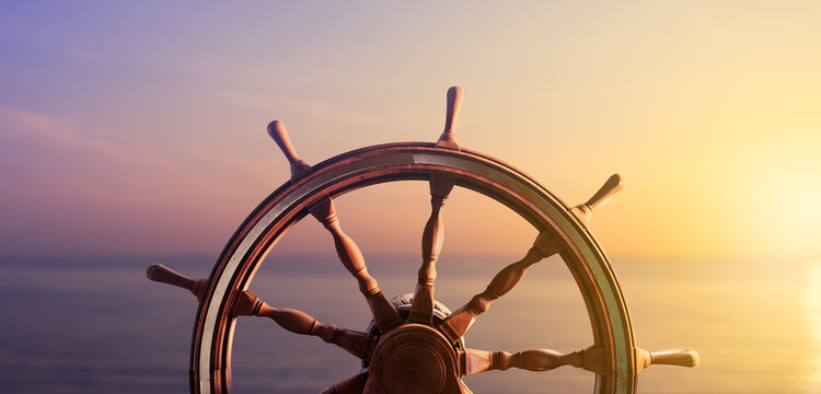 Ship steering wheel, commonly known as helm, with the ocean at sunset in the background. 3D Rendering, illustration