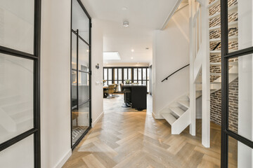 A spacious bright corridor with a wooden staircase and an entrance to the dining room with a window