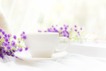 Coffee morning.  White steaming cup of hot coffee for relax after working hobbies crochet on white wooden near window with flowers.