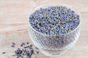 A bowl of dried lavender flower on wooden table.