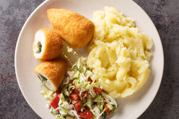 Ukrainian Dinner Chicken Kiev cutlets served with salad and mashed potatoes closeup in the plate on the table. Horizontal top view from above
