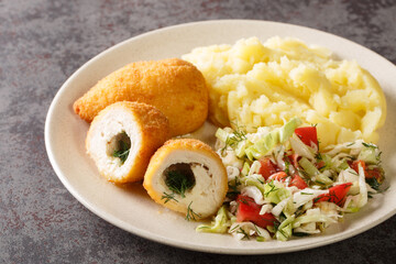 Chicken Kiev cutlets served with salad and mashed potatoes closeup in the plate on the table. Horizontal