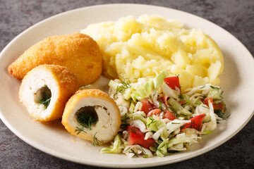 Chicken Kyiv also called cutlet de volaille basically a chicken fillet stuffed with parsley garlic butter, rolled up, breaded, and fried close-up in a plate on the table. horizontal