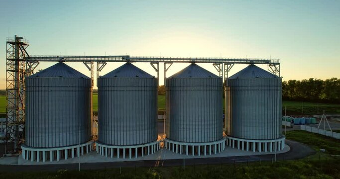 Grain elevator at sunset. Storage of grain crops. Agricultural industry Grain elevator. The sun's rays at sunset between the tanks.