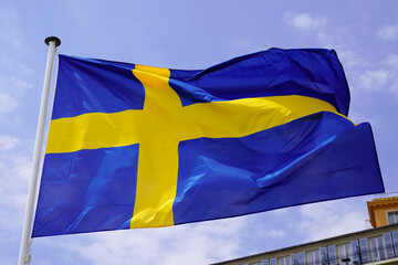 Flag of the Sweden against blue sky in fabric blue yellow cross colors