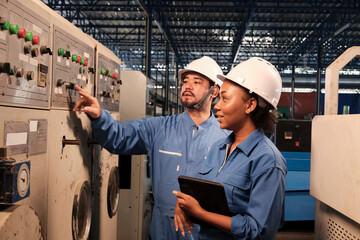 Professional industry engineer partner in hard hats and safety uniforms inspect machine's control panel, maintenance check with tablet in mechanical manufacture factory, electrical service occupation.