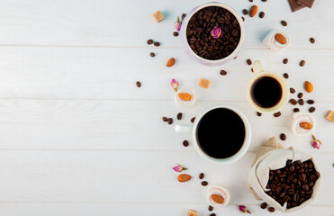 top view of coffee beans in a sack and cups of coffee on white background with copy space