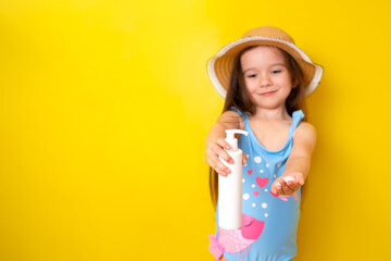 Sun protection. A little girl in a swimsuit and hat uses sunscreen. Yellow background, space for text.