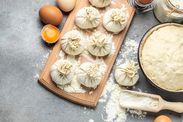 Raw Khinkali with meat on a wooden board. semi-finished products dumplings cooking khinkali on a dark background. Georgian dumplings. place for text, top view