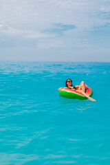 sexy woman swimming in blue sea on inflatable ring