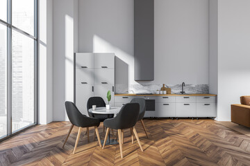 Light kitchen interior with eating table and chairs near panoramic window