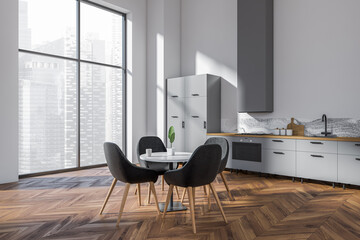 Light kitchen interior with eating table and chairs near panoramic window