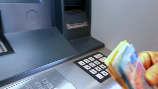 A person withdraws money at ATM , Euro banknotes and counts it. A woman withdraws money from a bank machine. 