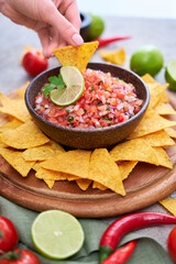 freshly made salsa dip sauce with nacho chips on wooden board