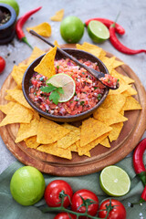 freshly made salsa dip sauce with nacho chips on wooden board