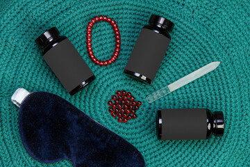 Blank black plastic beauty cosmetic jar with red fish oil capsules on green rug with pomade and...