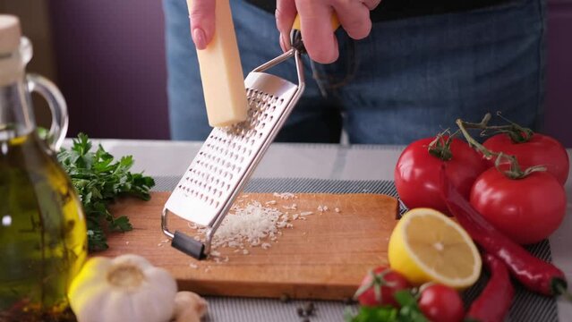 woman grates parmesan cheese for at domestic kitchen