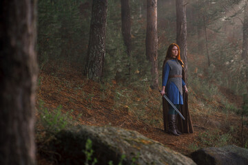 Red-haired girl in armor and raincoat in forest. Historical concept