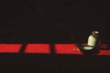 Light and shadows cast on a porcelain container and incense sticks showing the concept of...