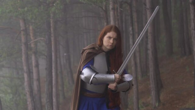 Portrait red-haired girl in medieval knight's armor in summer forest