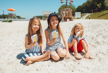 Three children eat ice cream on the beach. a child with down syndrome leads a normal life