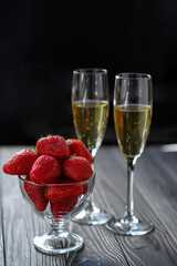 strawberries and champagne in a glass on a black background