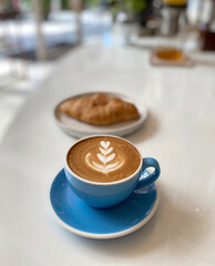 Hot coffee cup and croissant on table