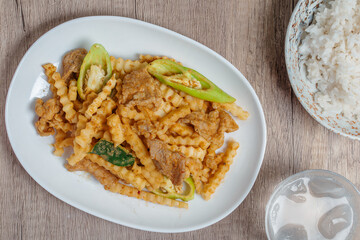Stir-fried pork with red curry paste and young coconut shoots in a white plate