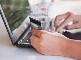Closeup hands holding credit card paying online at home office.