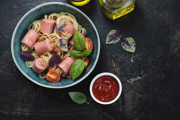 Bowl with threaded spaghetti hot dog bites on a dark-brown stone background, horizontal shot with copy space, view from above