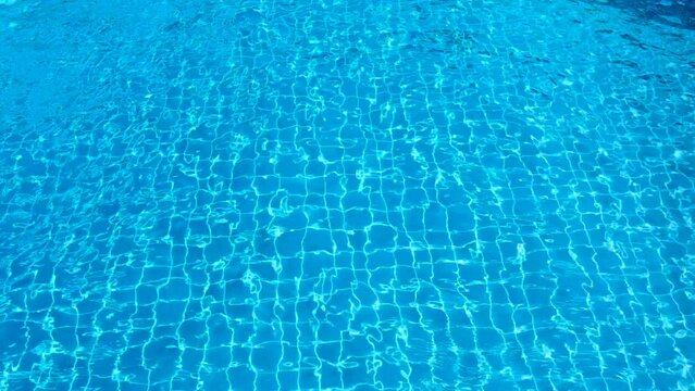Wavy pool water with bright blue background and grid tiled floor.