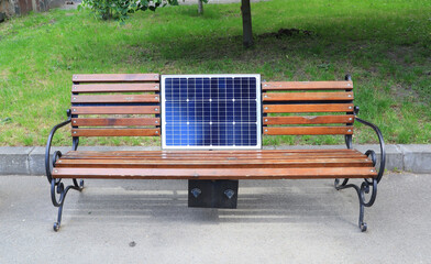 Wooden bench with solar panel (battery) in summer park
