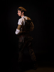 A guy in a steampunk image, a pilot or a mechanic. Retro style, fantastic image. portrait on black. Fantastic steam satchel behind back