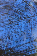Black streaks on a wet blue surface. Macro.