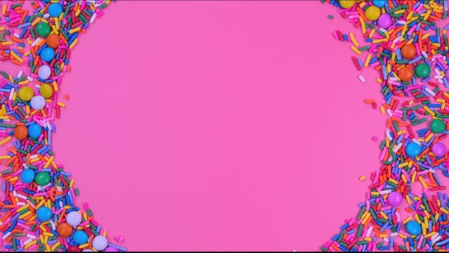 Rotating pink background with candies and sprinkles with place for text or copy space . concept for a celebrated birthday or party