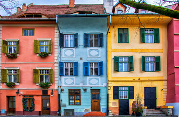 Naklejka premium Exterior of apartment buildings with balconies. Selective Focus. Buildings And Streets Of A Romanian City Called Sibiu. Windows Of Antique Buildings With Colourful Walls And Shutters. Architecture.