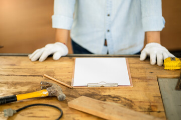 carpenter writes on a sheet of white paper, graphite pencil and clipboard with blank sheet of paper...