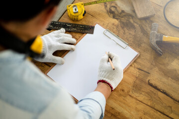 carpenter writes on a sheet of white paper, graphite pencil and clipboard with blank sheet of paper for text or design.