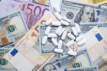 Pills on the background of the dollar and the euro close-up.