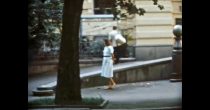 Woman walking on 80s Europe city street in summer. Person looking landmarks, old buildings in sun day. Travel attraction, urban view. Vintage color film. Cityscape archive. Retro 1980s Kyiv Ukraine