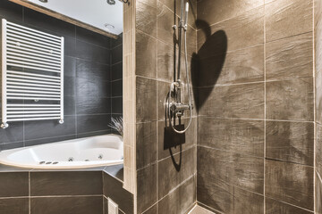 Modern styled black tiled bathroom with a bath and shower cabinet