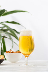 One glass light beer with foam overflowing amber beverage