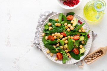 Overhead view of healthy food vegan avocado salad with greens and chick pea on light surface