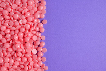 Beautiful pink depilation hot wax granules on violet background. Depilatory wax. Epilation,...