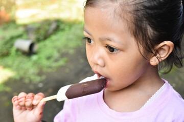 close-up of asian little girl eating ice cream while looking away