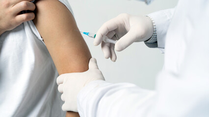 A male doctor gives an injection inoculation in the patient's shoulder
