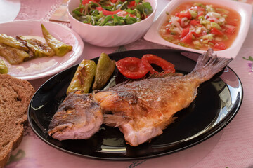 On the table , Fried sea bream in a black plate