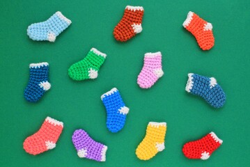 Winter christmas colourful crochet knitted socks on green background. Stockings gift New Year season sale concept. Top view flatlay out idea for present decor postcard, banner. Odd socks day lost pair