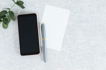 Flat lay of greeting card, pen and smart phone on gray background.