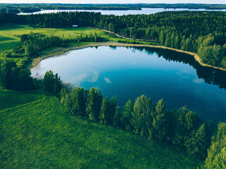 Aerial view of blue lakes and green fields with woods in Finland.